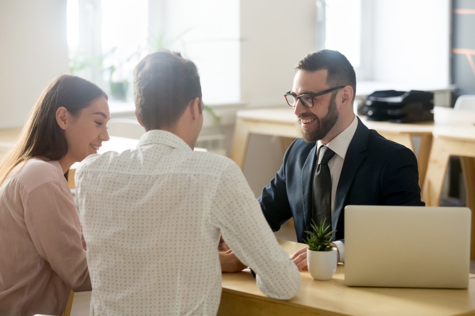 Smiling advisor meeting with a young couple in a modern office to discuss options.